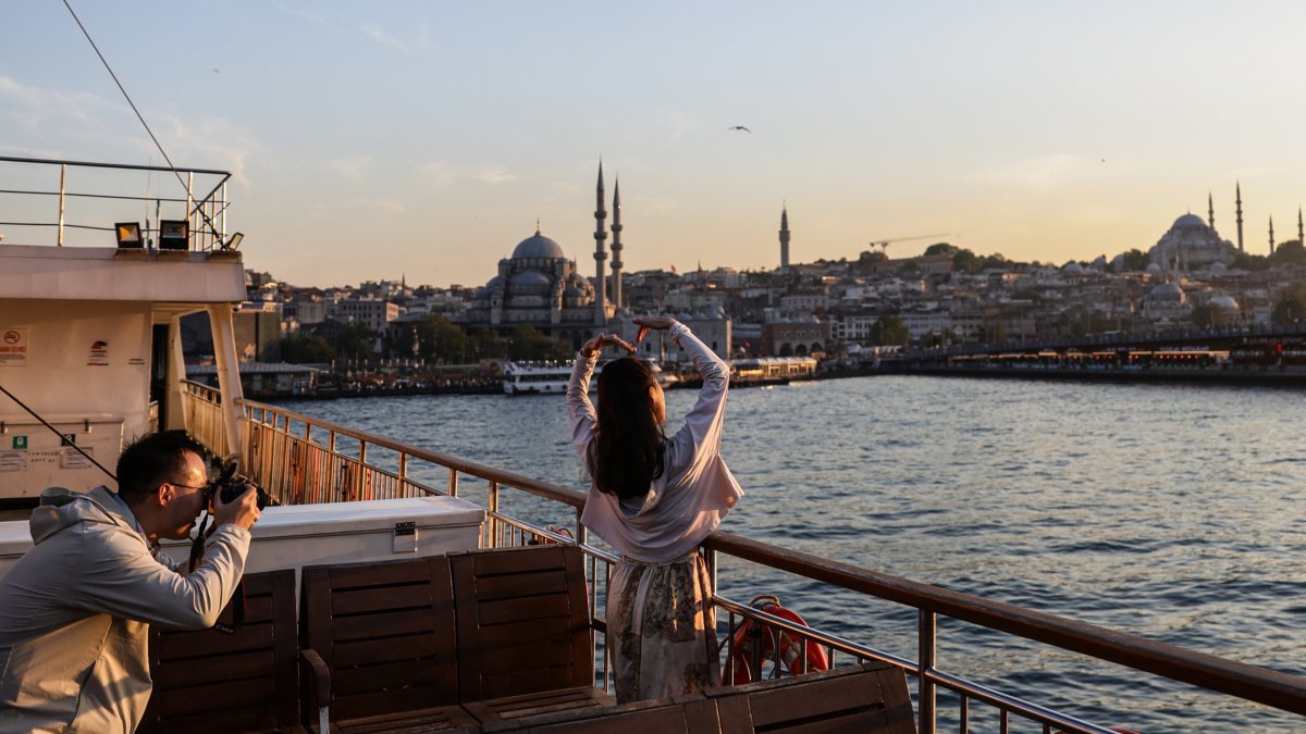 Tourists pose on a ferry backdropped by the Süleymaniye Mosque and the New Mosque in Eminönü during sunset in Istanbul, Türkiye, May 28, 2025. (EPA Photo)