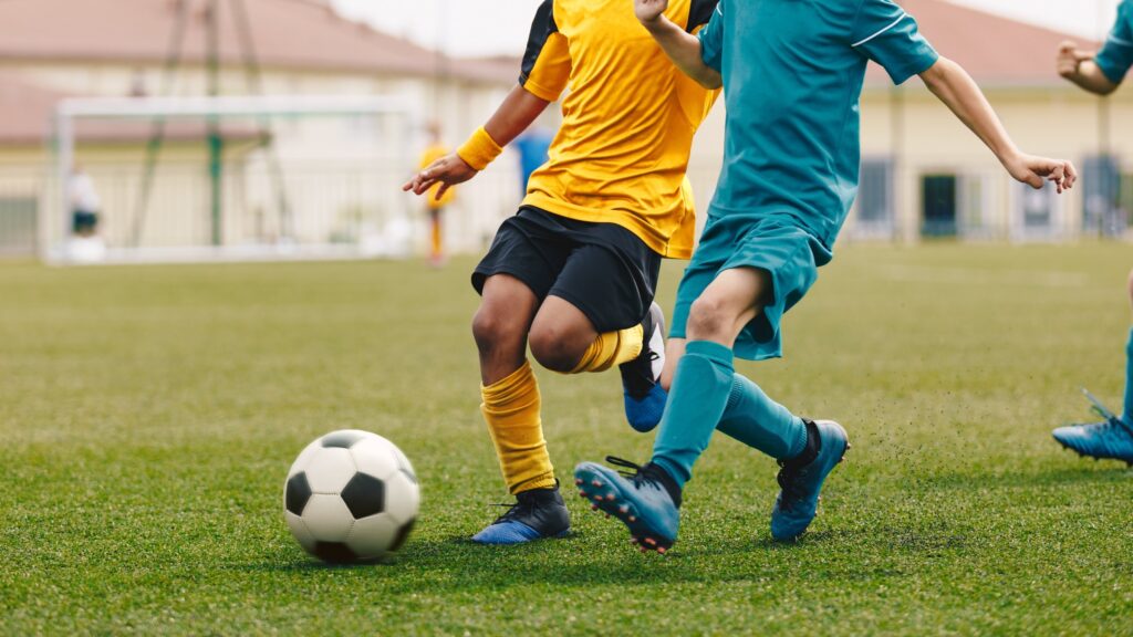 Young boys play football at a stadium during a sports event. (Shutterstock Photo)