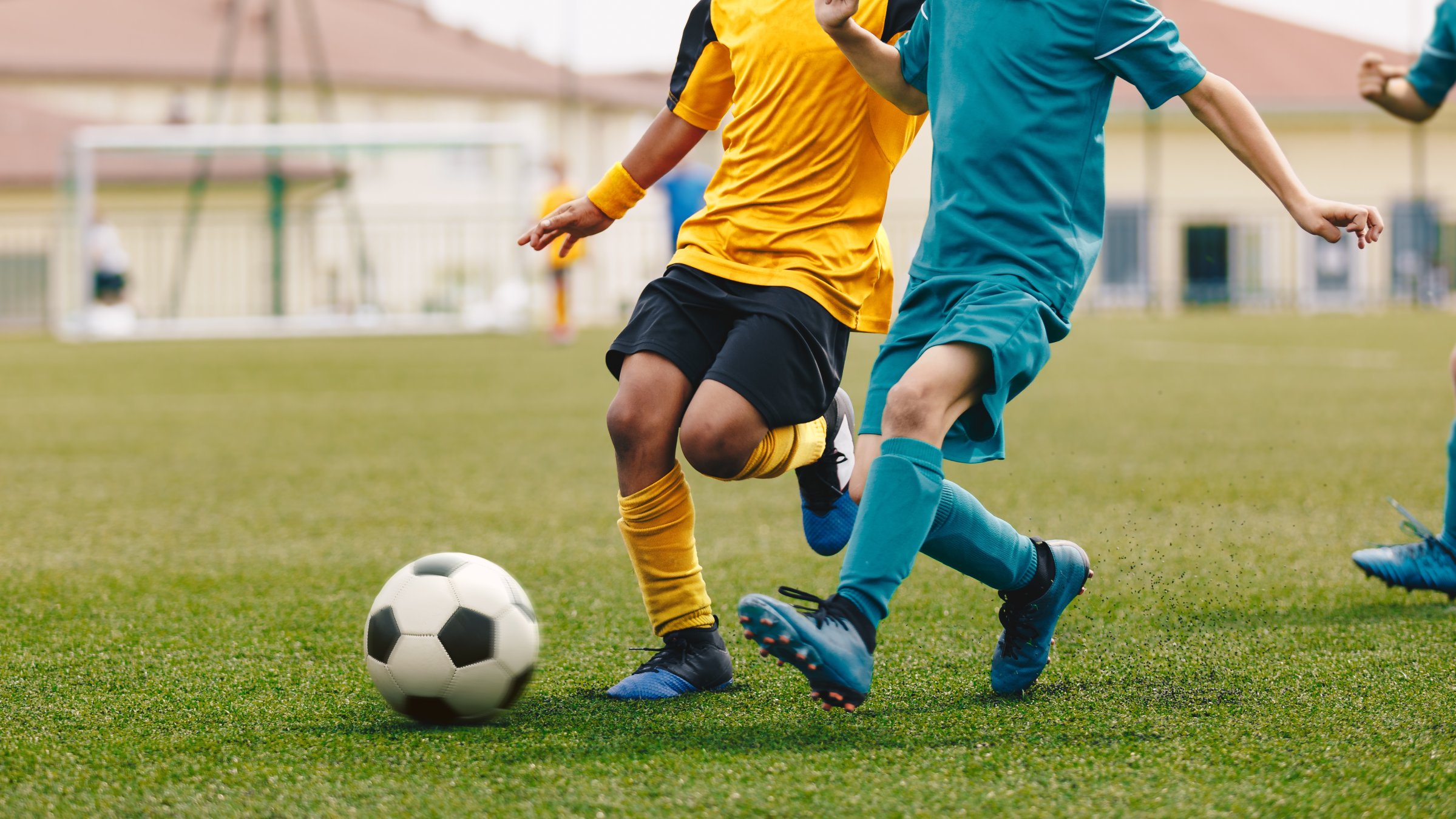 Young boys play football at a stadium during a sports event. (Shutterstock Photo)