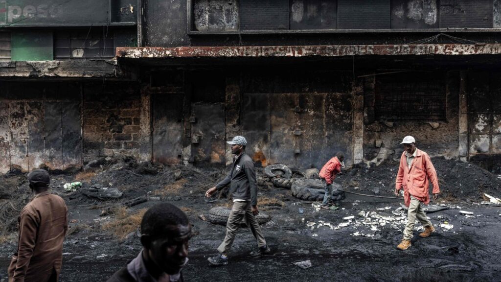 Residents walk past a shopping center that was vandalized and torched during deadly protests marking one year since the storming of Parliament in anti-tax demonstrations, Nairobi, Kenya, June 26, 2025. (AFP Photo)