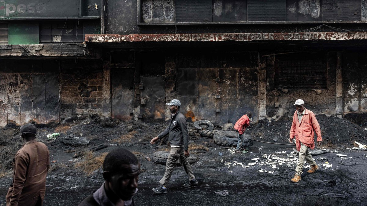 Residents walk past a shopping center that was vandalized and torched during deadly protests marking one year since the storming of Parliament in anti-tax demonstrations, Nairobi, Kenya, June 26, 2025. (AFP Photo)