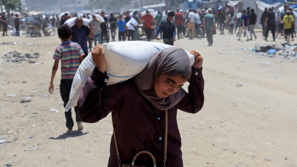A Palestinian carries a sack of flour as people gather to receive aid supplies in Khan Younis, in the southern Gaza Strip, June 26, 2025. (Reuters Photo)