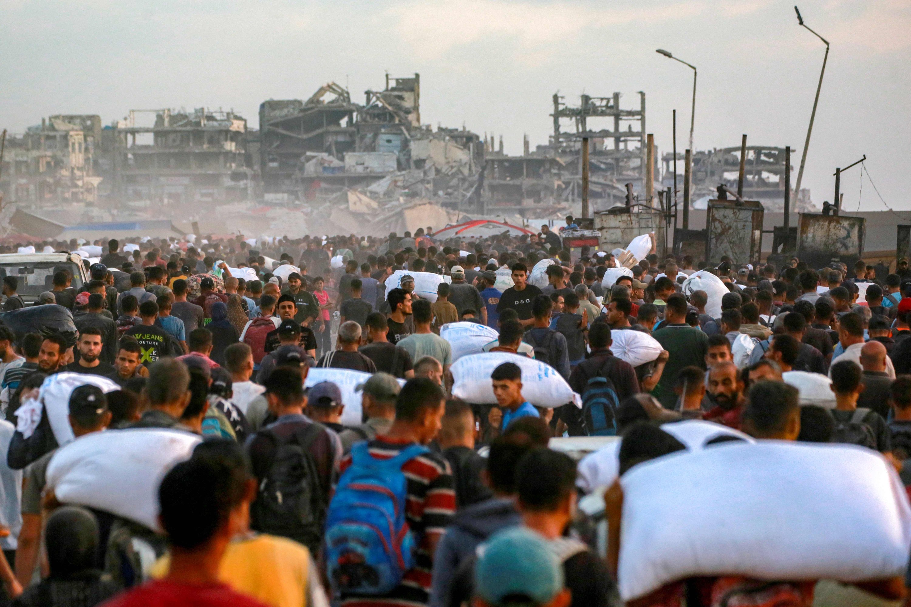 389177 People carrying sacks of flour walk along al-Rashid street in western Jabalia, June 17, 2025. (AFP Photo)