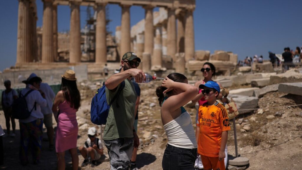 A man tries to cool a girl with water during their visit to the Parthenon temple atop the Acropolis hill, as a heatwave hits Athens, Greece, June 27, 2025. (Reuters Photo)