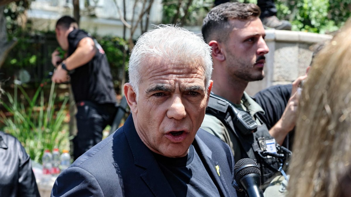 Israel's opposition leader and member of Parliament, Yair Lapid, speaks to a journalist as he visits the Ramat Aviv area in Tel Aviv, following an Iranian strike that hit the residential neighborhood, June 22, 2025. (AFP Photo)