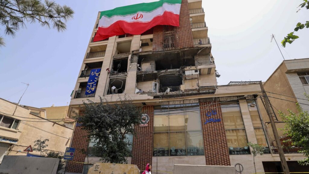 A woman walks past a residential building that was hit in an Israeli strike covered with a big Iranian flag, in Tehran, Iran, June 25, 2025. (AFP Photo)