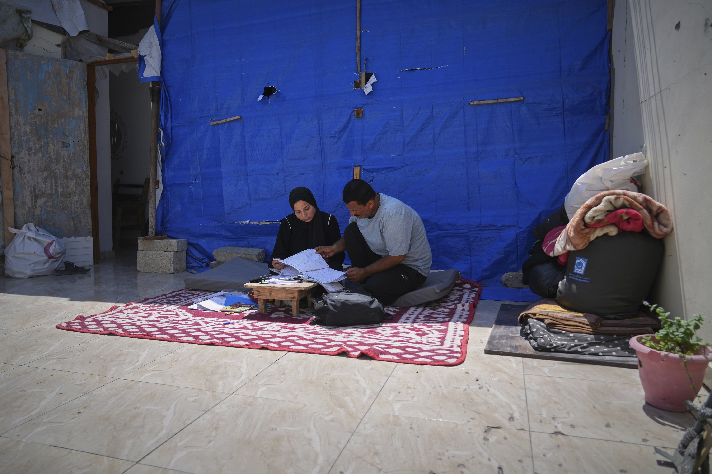 392714 Sarah Qanan studies with her father, Ibrahim, in their family's tent in Khan Younis, Gaza Strip, Palestine, June 28, 2025. (AP Photo)