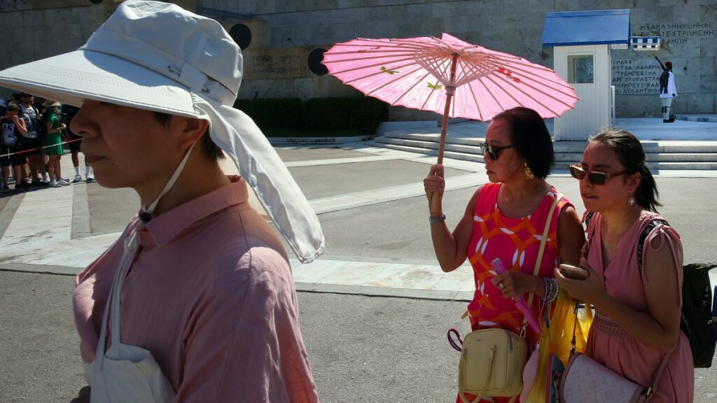 Tourists wear hats and use fans and umbrellas as they stroll in the city center during a heat wave, Athens, Greece, July 20, 2025. (EPA Photo)