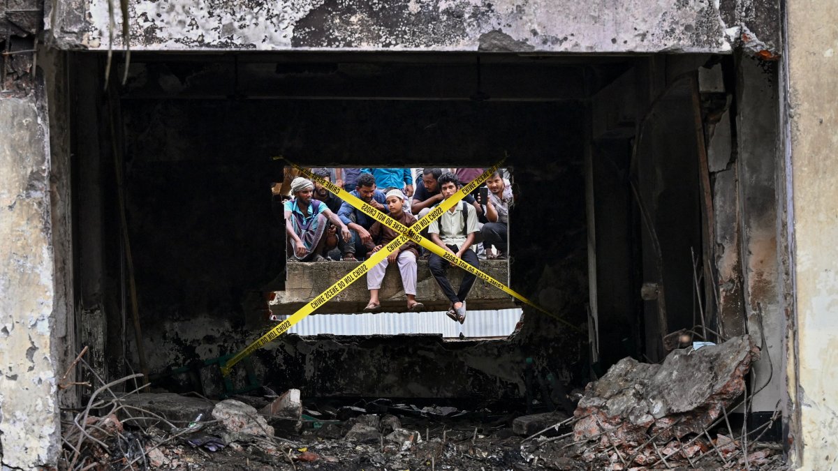Onlookers gathered behind crime scene barrier tape, cordoning off the crash site in Dhaka, Bangladesh, July 22, 2025. (AFP Photo)