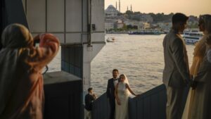 Couples wearing their wedding outfits pose during a photo session at Galata Bridge, in Istanbul, Türkiye, July 28, 2025. (AP Photo)