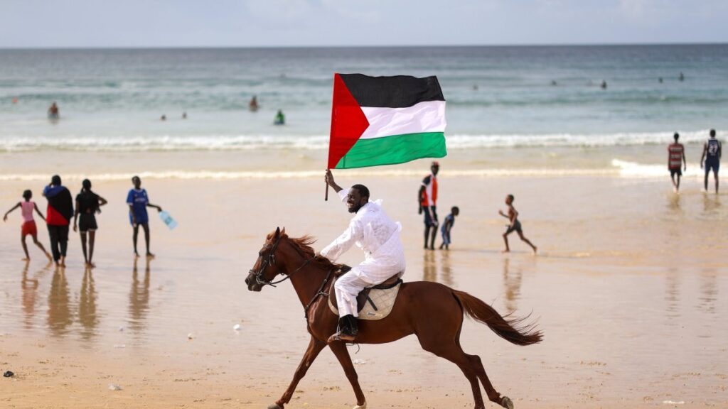 Senegalese artist Thierno Gueye carries the Palestinian flag on horseback to show solidarity with Gaza at Yoff Beach, Dakar, Senegal, Aug. 10, 2025. (AA Photo)