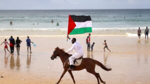 Senegalese artist Thierno Gueye carries the Palestinian flag on horseback to show solidarity with Gaza at Yoff Beach, Dakar, Senegal, Aug. 10, 2025. (AA Photo)